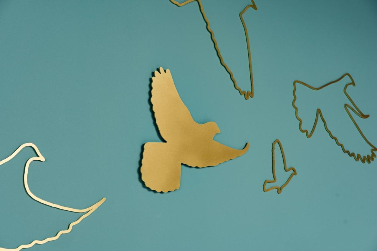 Middle Eight - Covent Garden - Preferred Hotels And Resorts London Ngoại thất bức ảnh The photo shows a collection of metallic gold bird silhouettes against a solid turquoise background. The birds are depicted in various positions and styles, showcasing different species and flight postures. Some silhouettes are more detailed, while o
