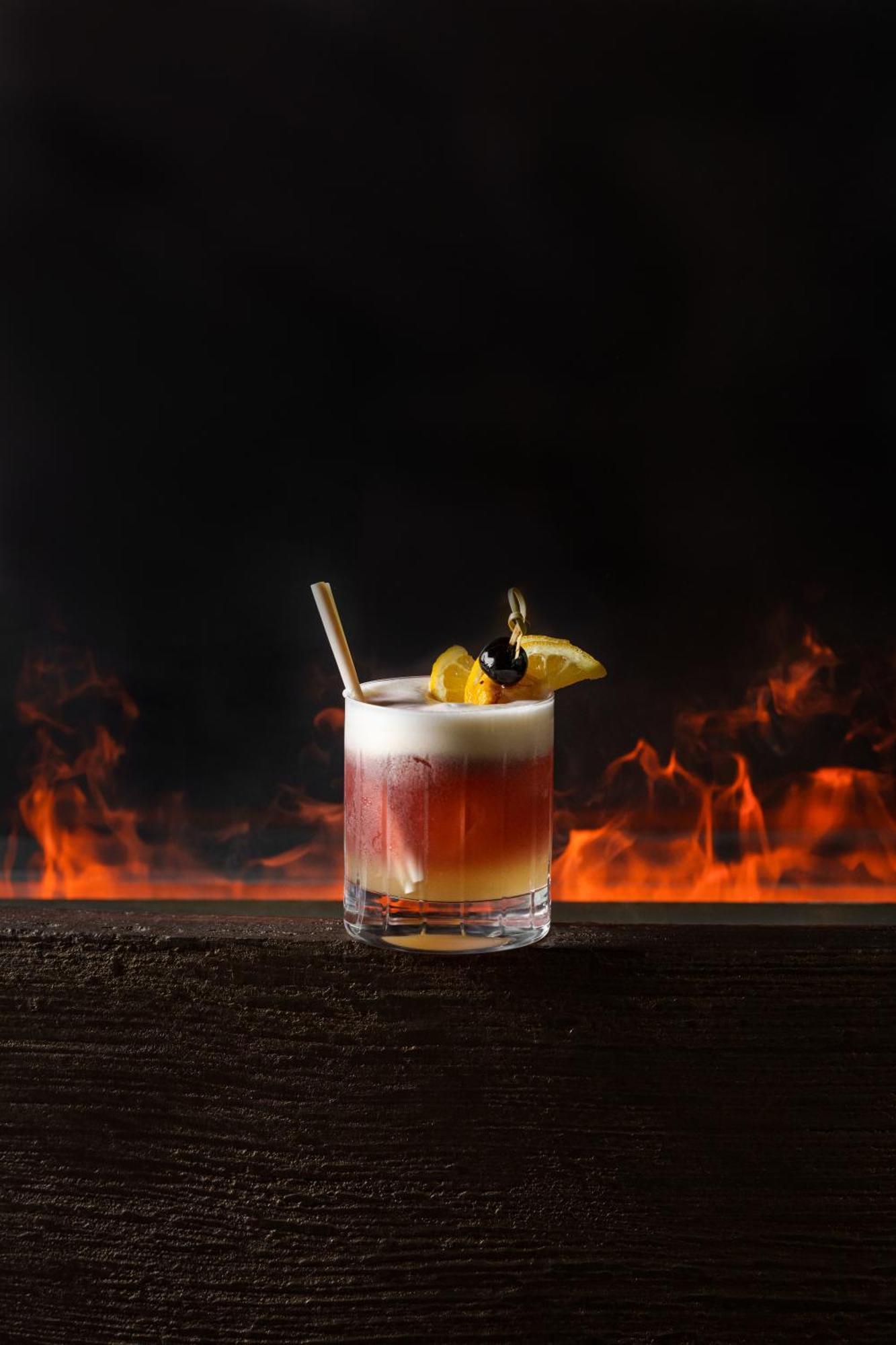 Middle Eight - Covent Garden - Preferred Hotels And Resorts London Ngoại thất bức ảnh The image shows a cocktail presented in a clear glass with a thick base. The drink features layered colors, transitioning from a deep reddish hue at the bottom to a lighter, frothy layer on top. It is garnished with a slice of lemon and a cherry, and