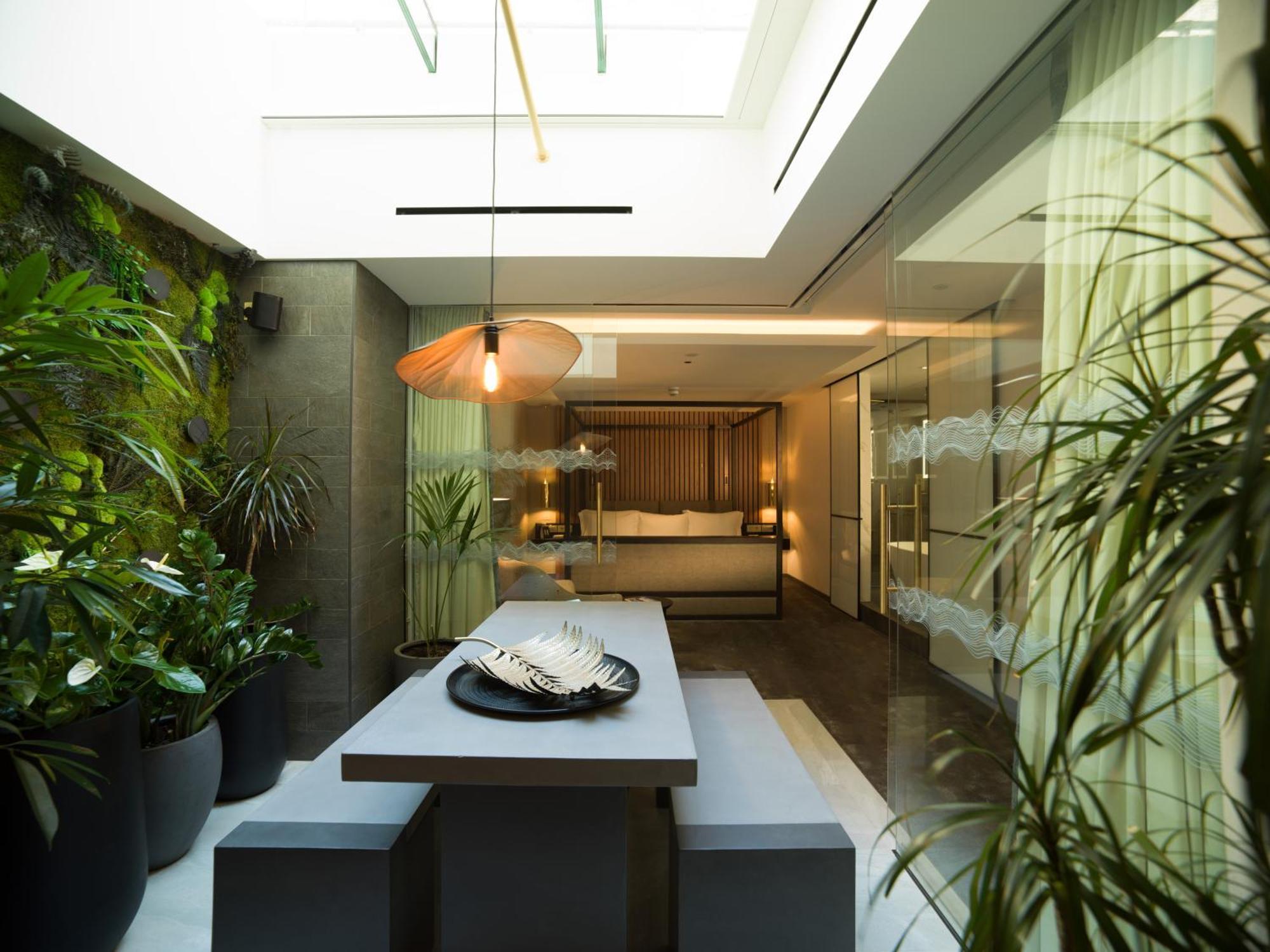 Middle Eight - Covent Garden - Preferred Hotels And Resorts London Ngoại thất bức ảnh The photo depicts a modern, airy interior space that features a dining area. The dining table is rectangular and made of a light-colored material, paired with simple benches on either side. Above the table, there is a stylish pendant light, providing